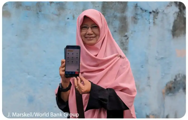 Lady using a mobile phone to pay at a vegetable market