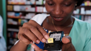 A woman inserting a new SIM card into a mobile phone in Abidjan, Côte d’Ivoire. Photo © Nyani Quarmyne/International Finance Corporation