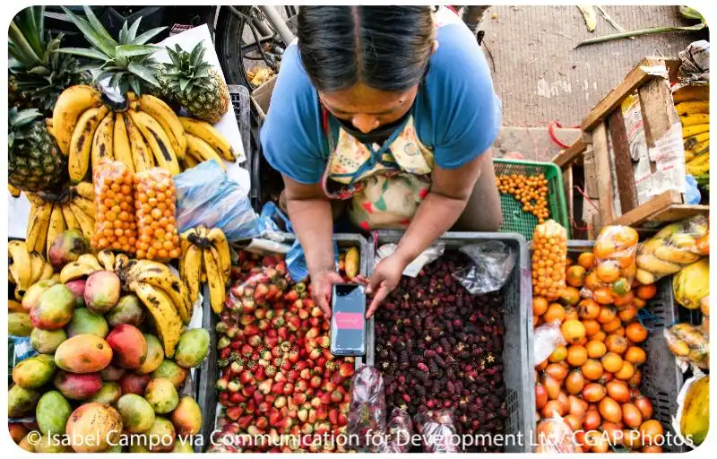 Female using a mobile phone to get paid in a street fruit market